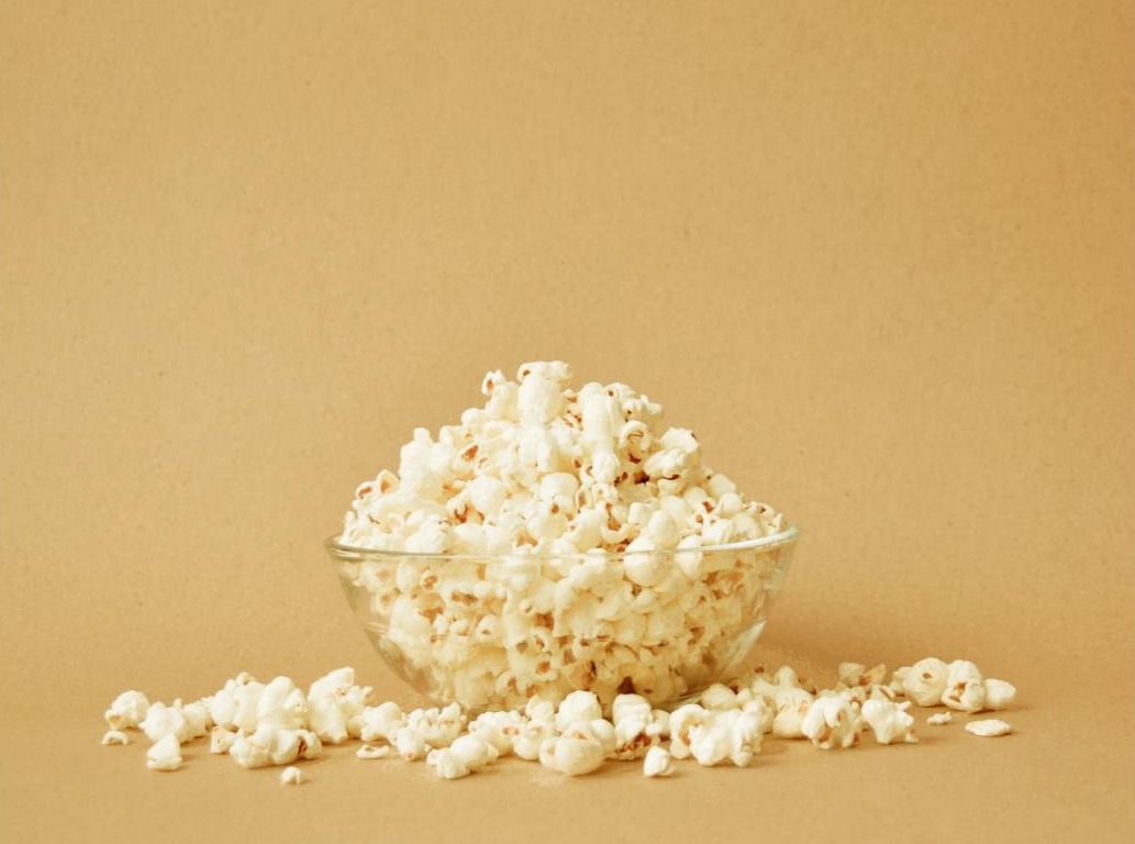 A glass bowl overflowing with freshly popped popcorn