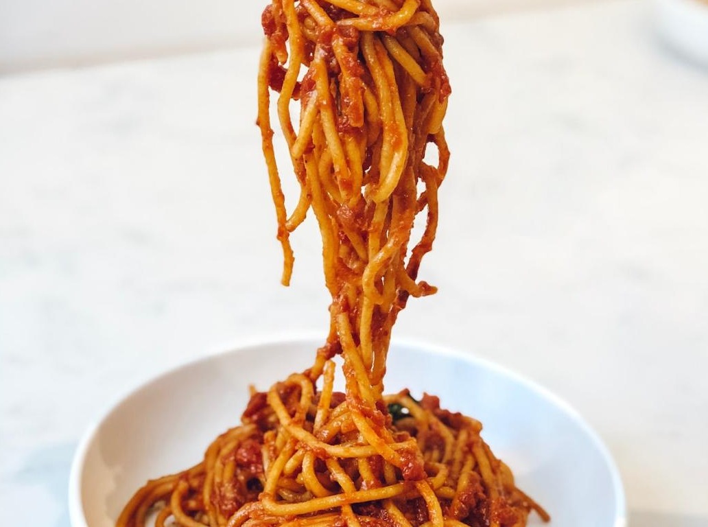 Italian spaghetti lifted from a bowl of rich marinara sauce