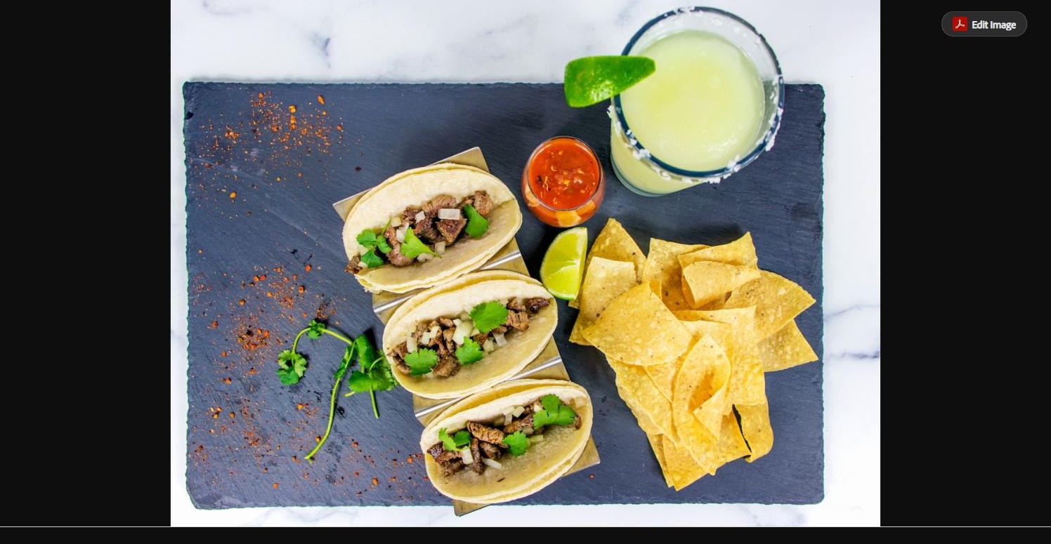 Mexican street tacos topped with cilantro and onion, served with salsa, lime, and tortilla chips